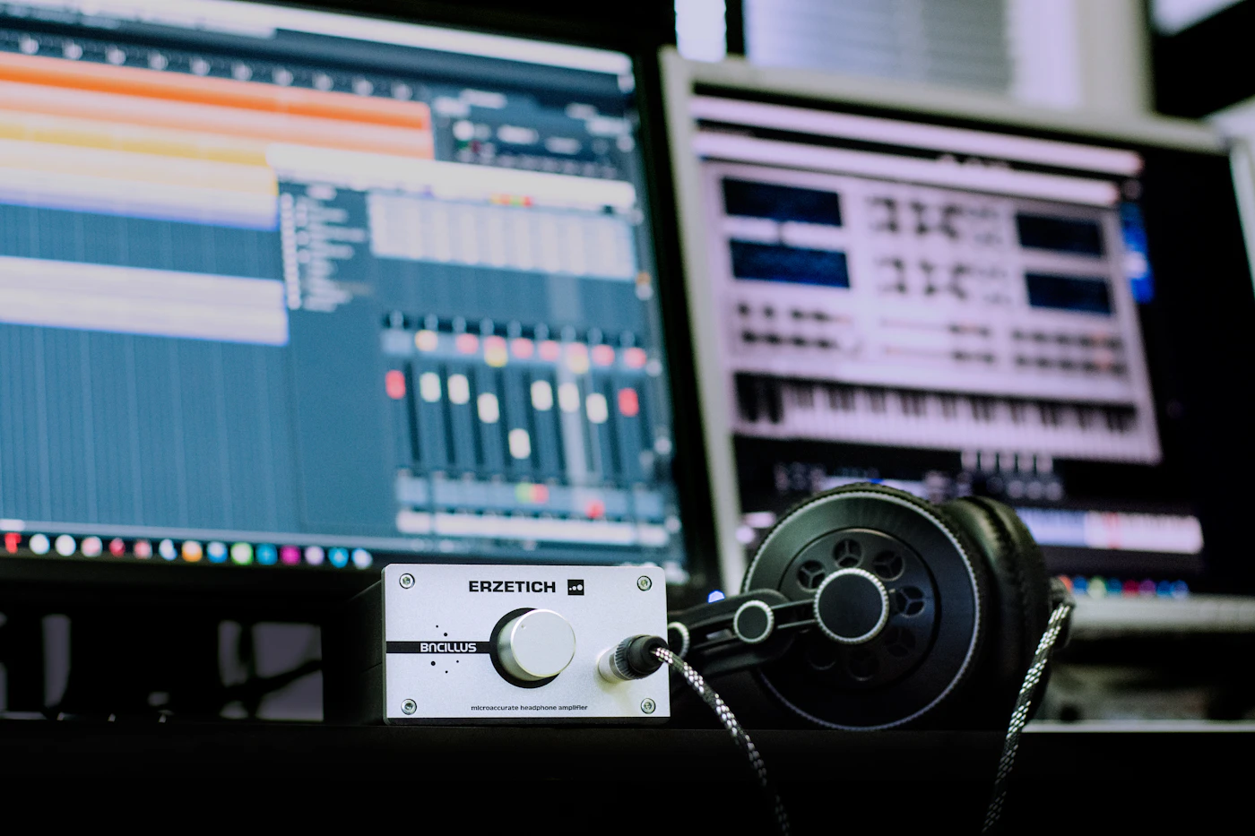 Studio headphones beside a computer running music production software