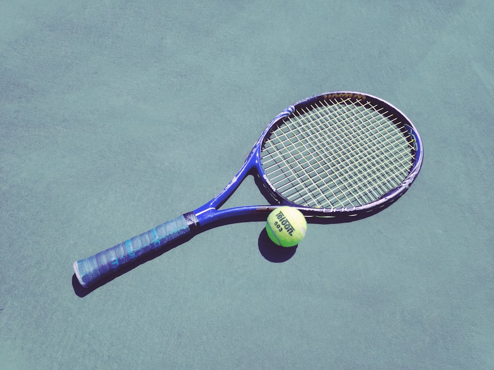 raquette de tennis bleue et balle Wilson verte