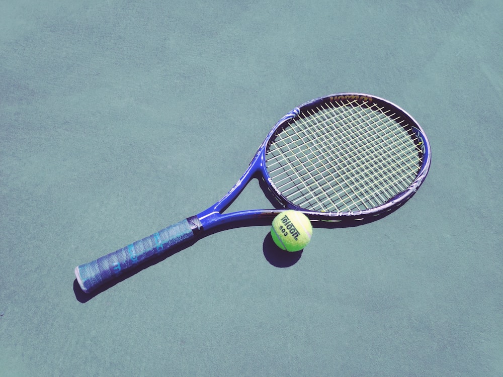 blue tennis racket and green Wilson ball