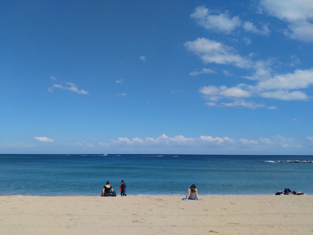 people on shore \facing ocean under blue sky