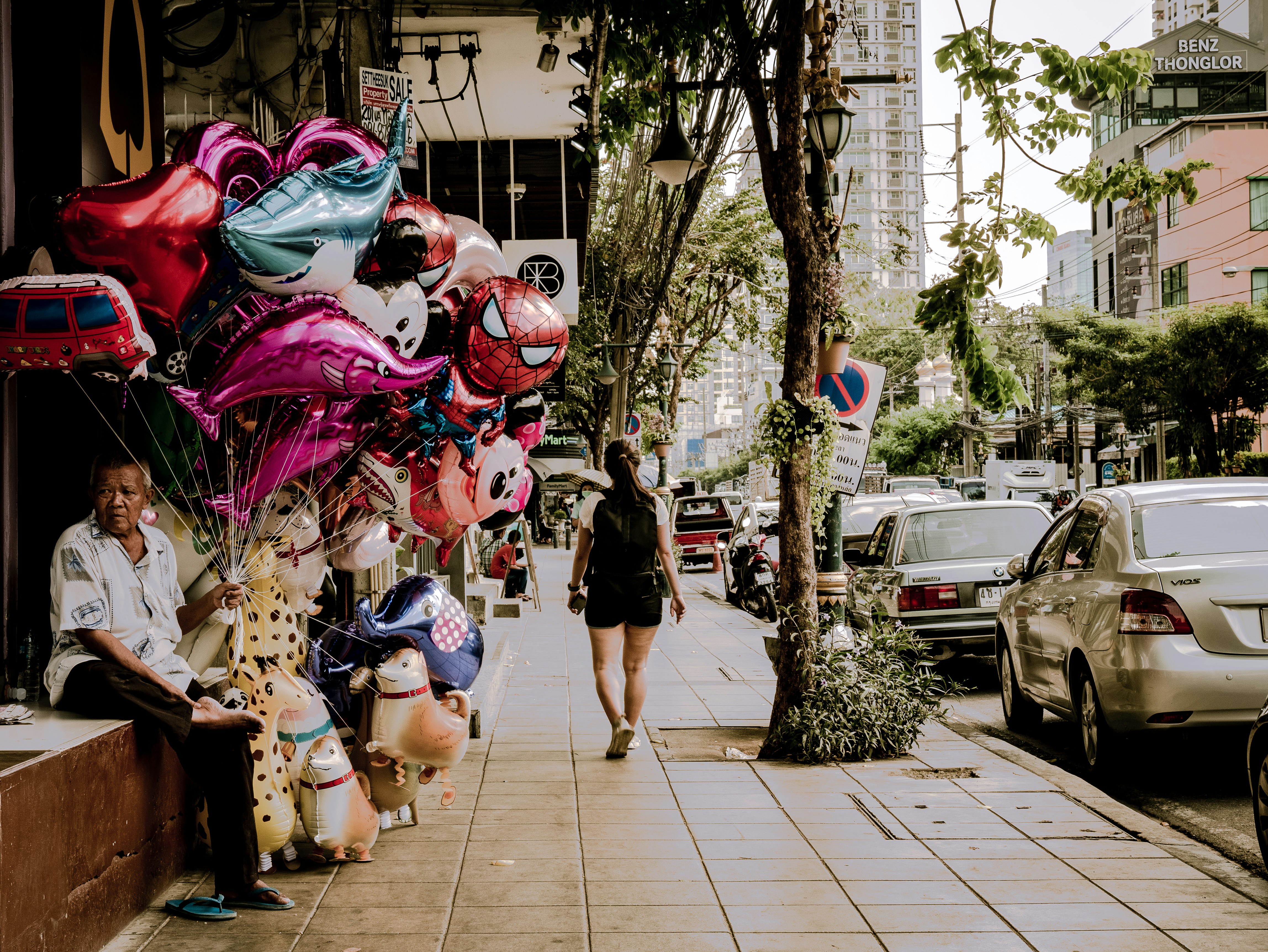 person holding balloons on sidewalk