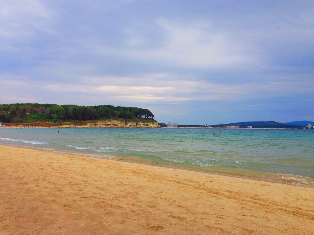 Vista de la orilla del mar mar en calma bajo cielos blancos y azules