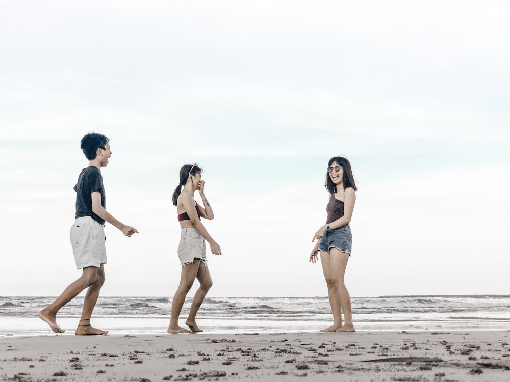 three persons standing on shore
