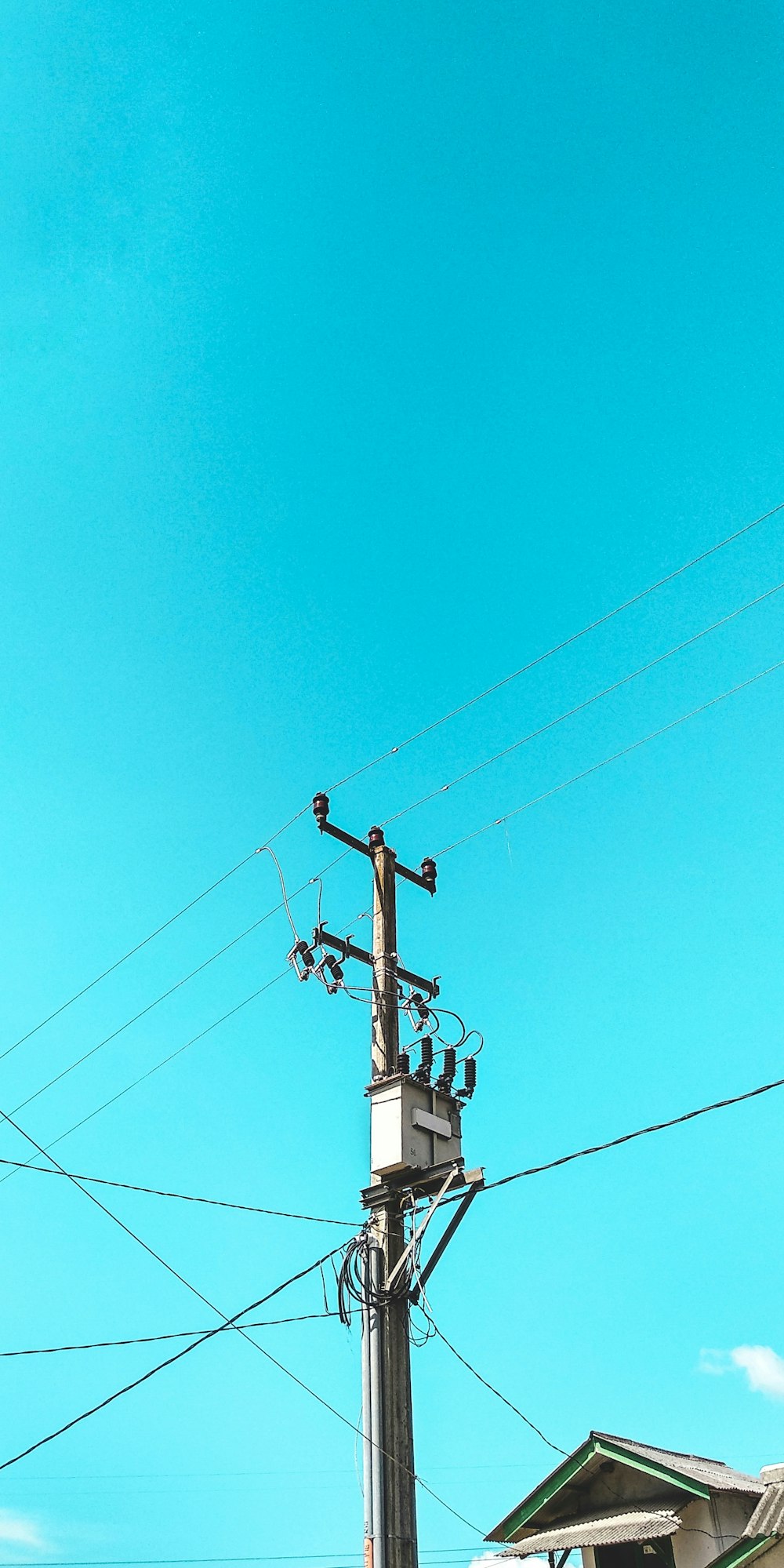 white and gray electric post under blue skies