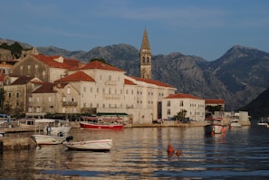 white and red boats on body of water near buildings