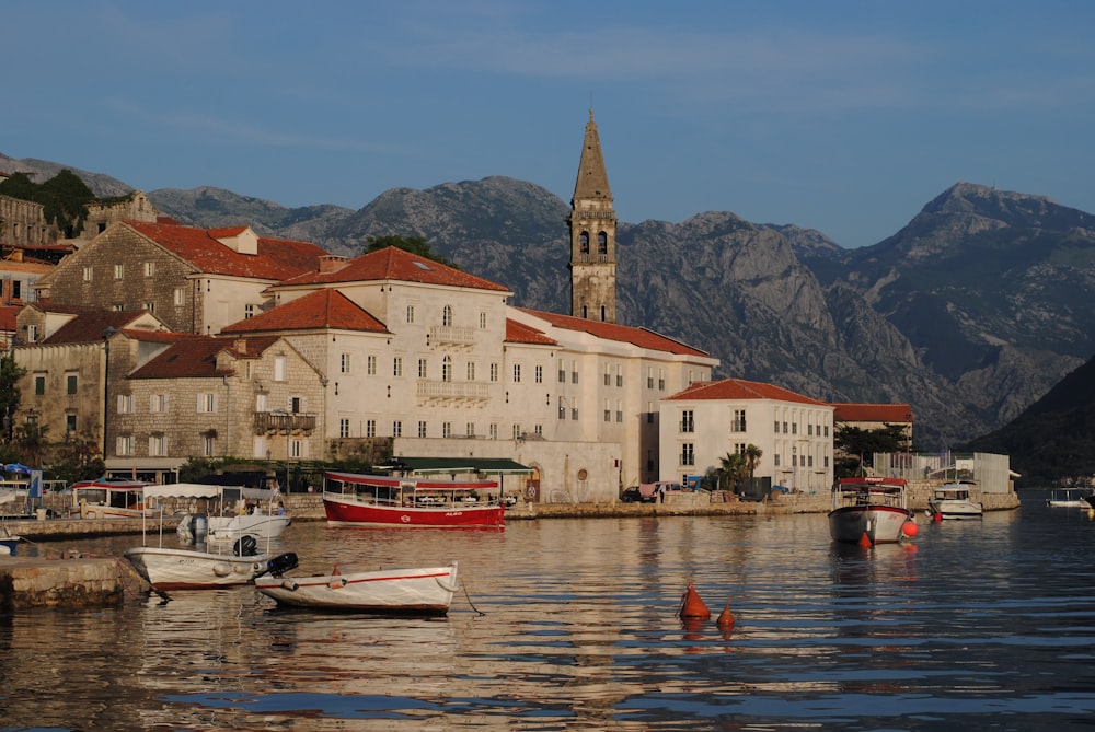 white and red boats on body of water near buildings