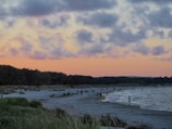 Sunset over a peaceful Lefkada beach with people strolling along the shore