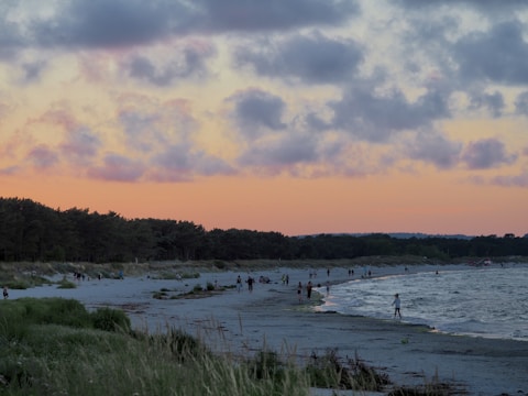 Sunset over a peaceful Lefkada beach with people strolling along the shore