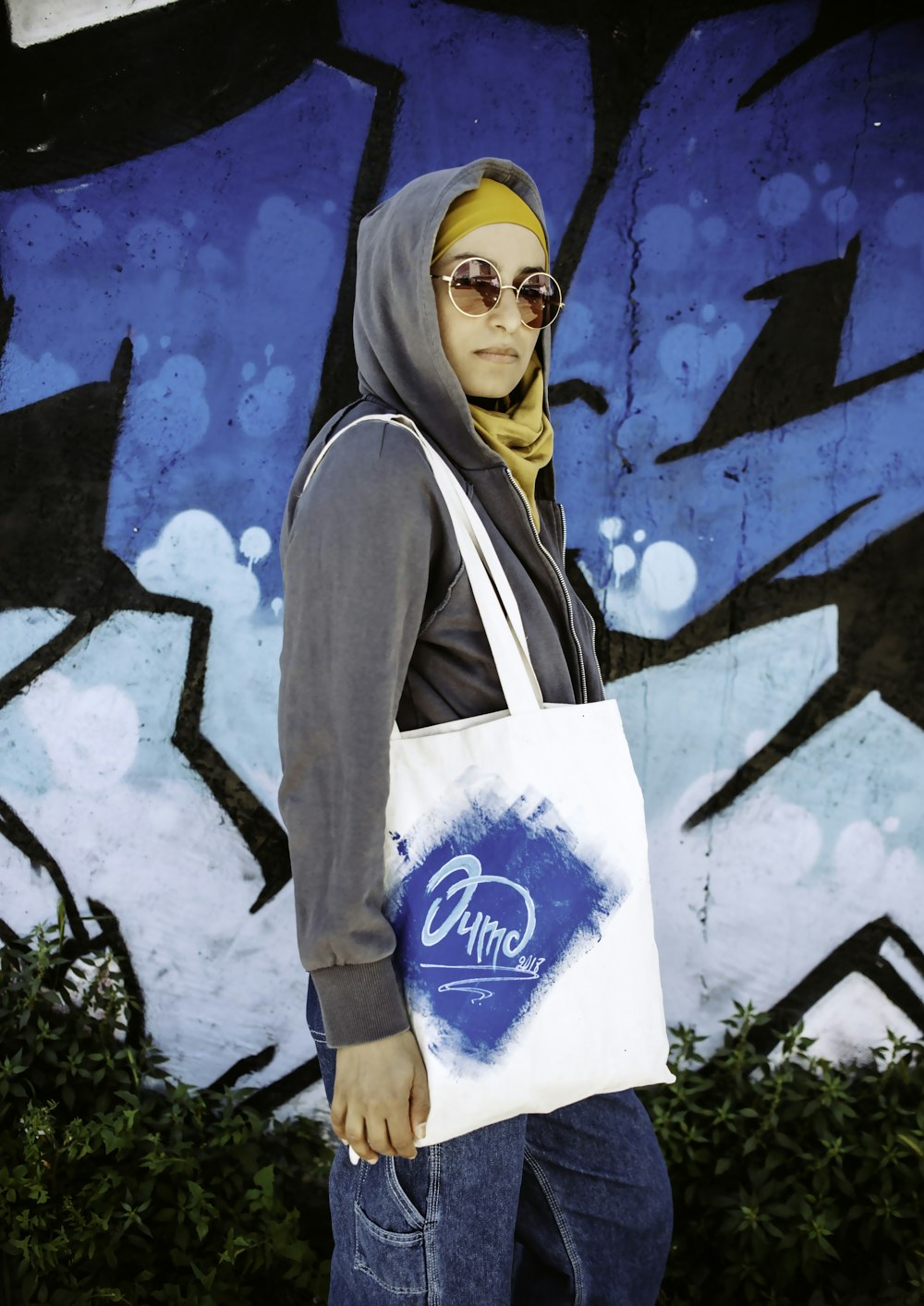 woman wearing grey hoodie carrying white shoulder bag