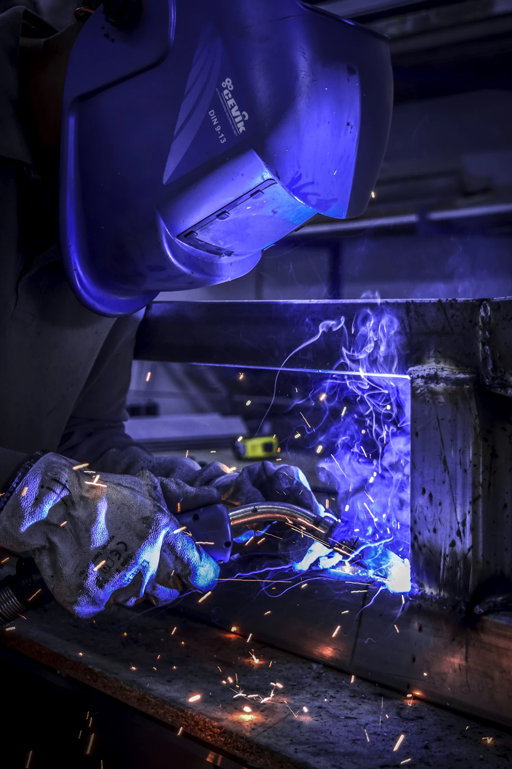 A welder joining a structural steel frame connection with a welding torch