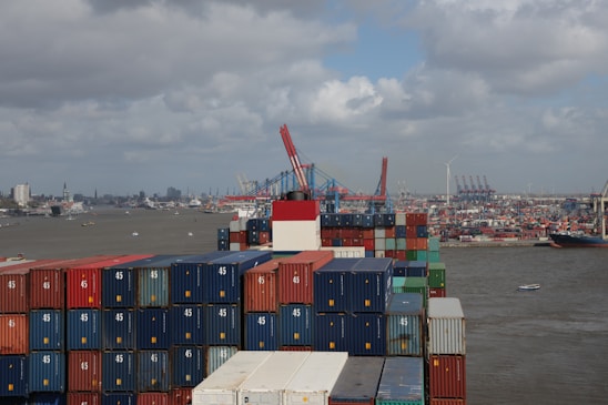 A team of workers securing containers on a cargo ship at a bustling port.