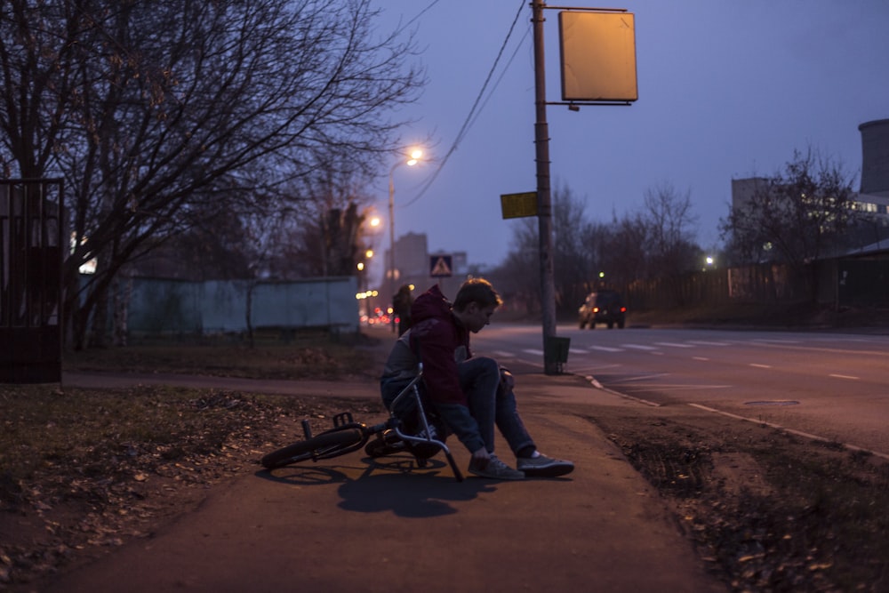 man sitting on sidewalk during nighttime