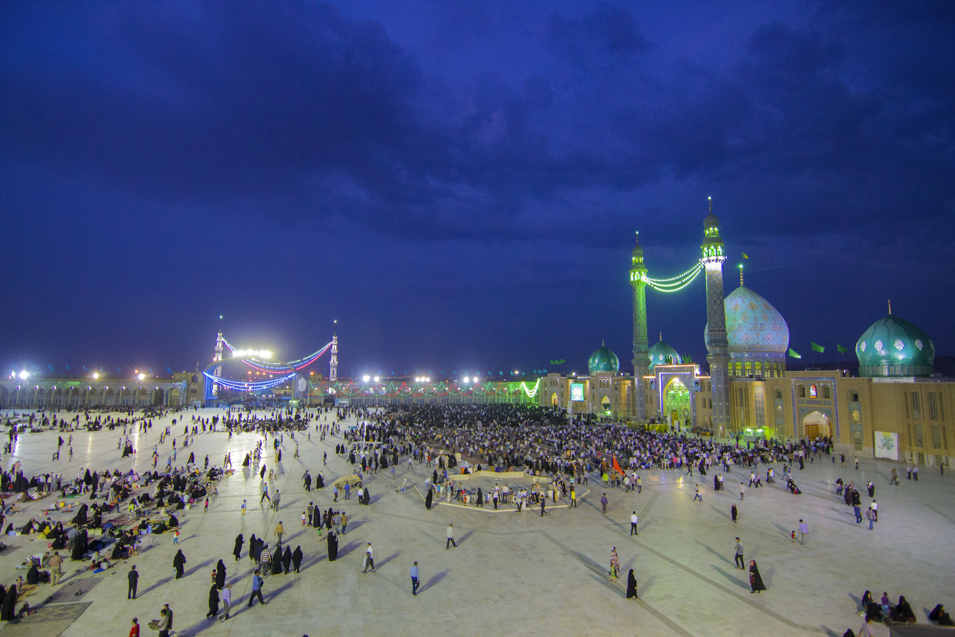 A panoramic shot capturing the bustling courtyard of Masjidil Aqsa with worshippers and visitors under a twilight sky.