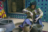 Hands of an older woman mixing fresh herbs in a traditional clay pot, capturing the art of ancestral cooking.