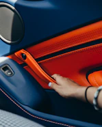Hands upholstering a car door panel with soft fabric material.