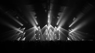 Rows of LED stage lights casting colorful beams across an empty concert hall.