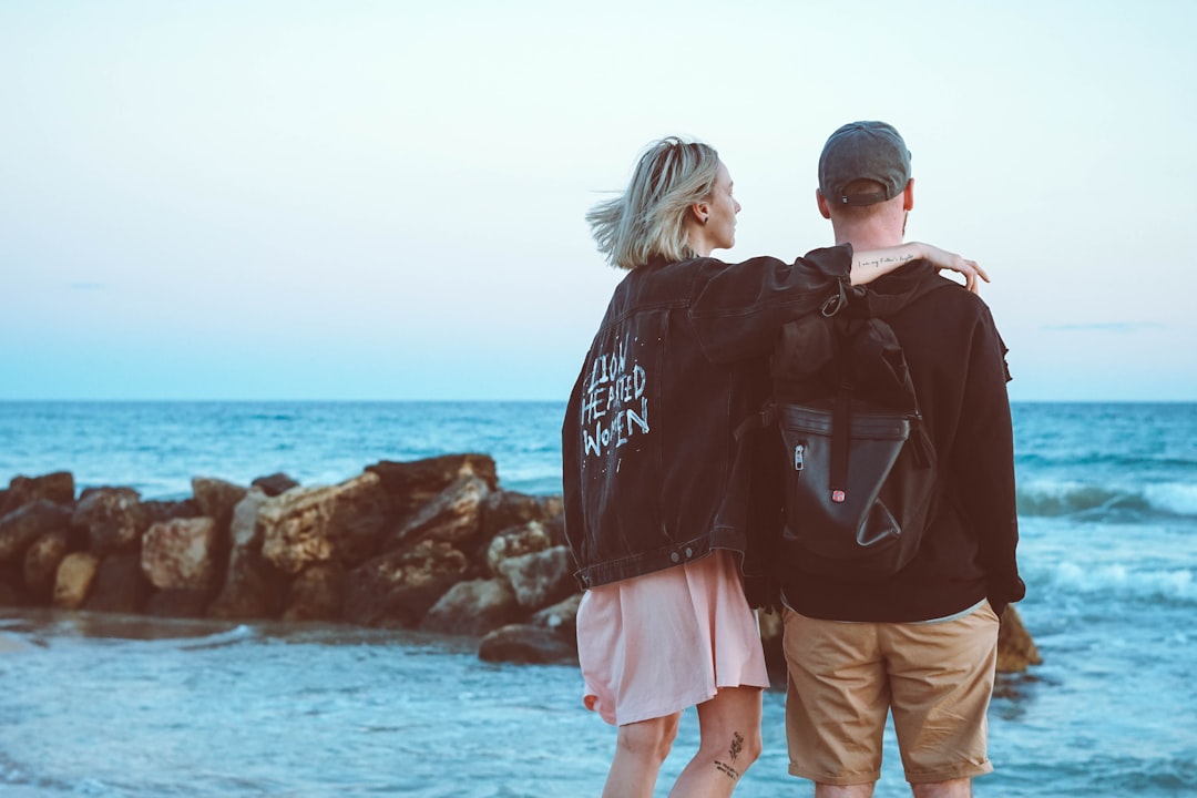 man and woman standing near beach line