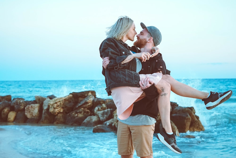 man carrying woman near body of water