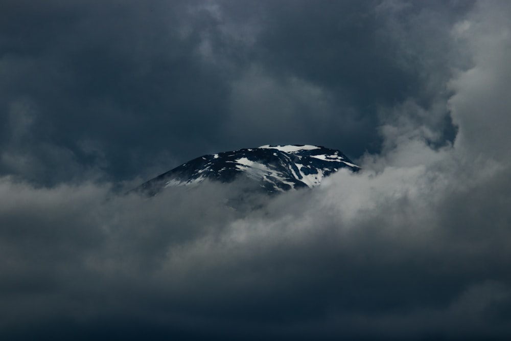 a snow covered mountain surrounded by dark clouds
