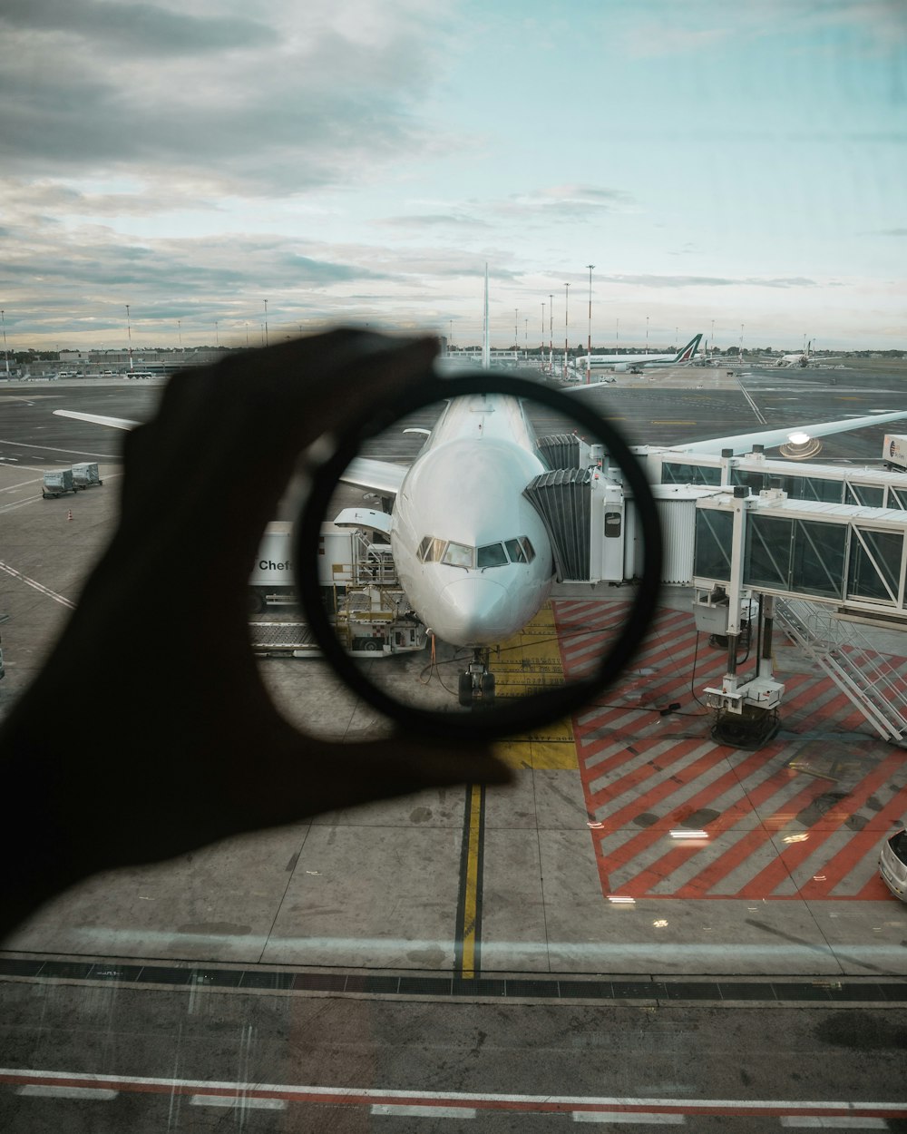 person holding lens through window with airliner plane during daytime