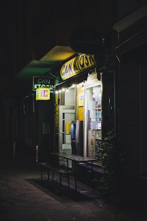 Evening shot of a defibrillator station glowing softly outside a neighborhood shop.