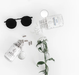 black framed hippie sunglasses beside glass bottle