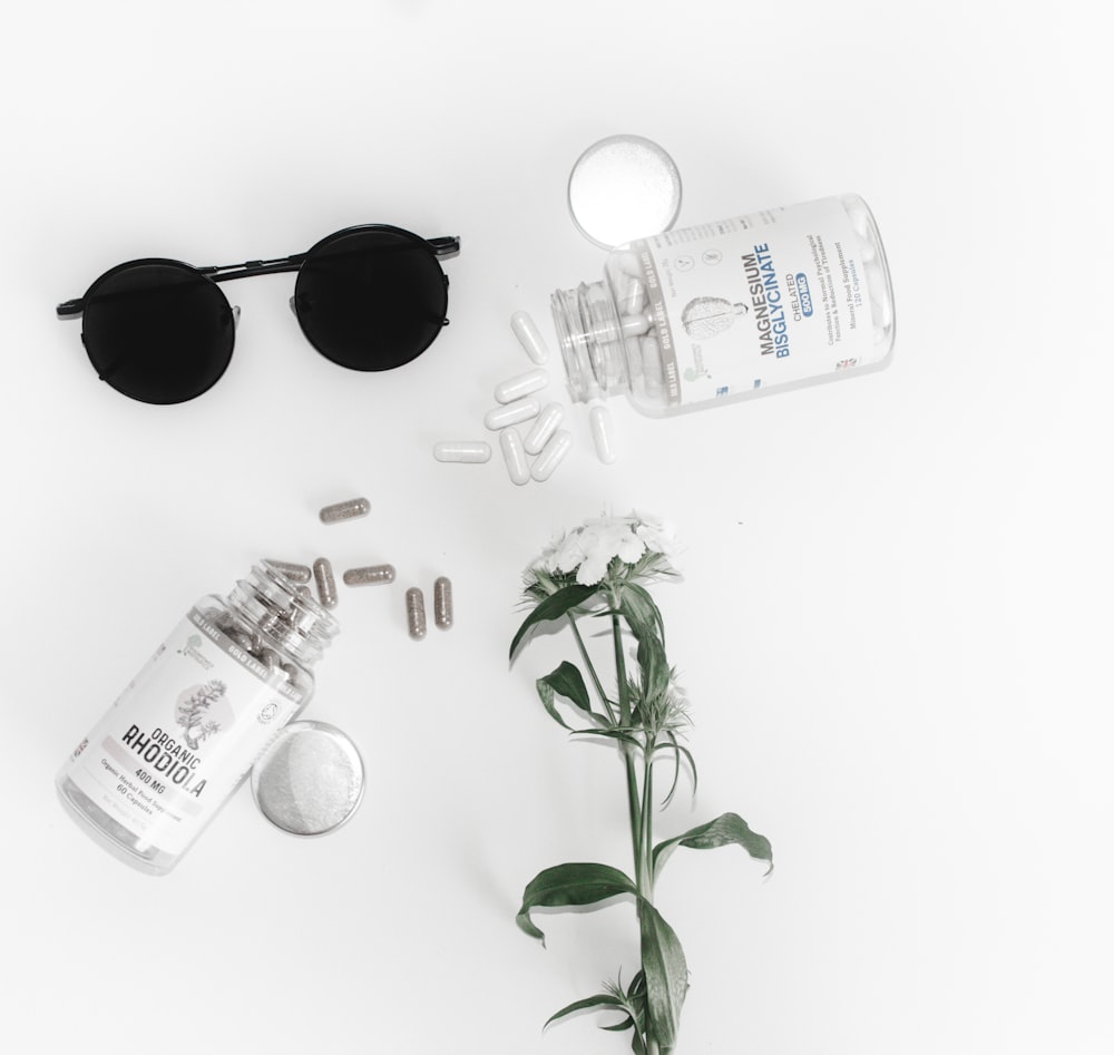black framed hippie sunglasses beside glass bottle