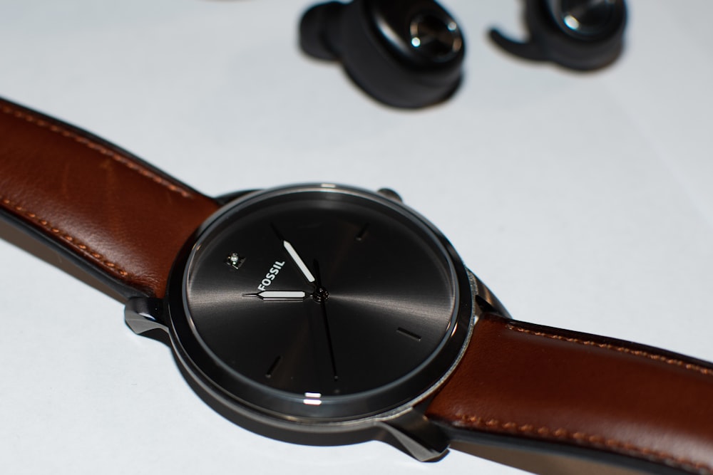 shallow focus photo of round black Fossil analog watch with brown leather strap
