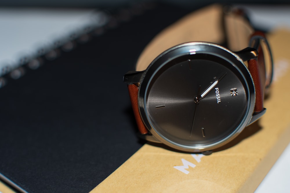 shallow focus photo of round black Fossil analog watch with brown leather strap