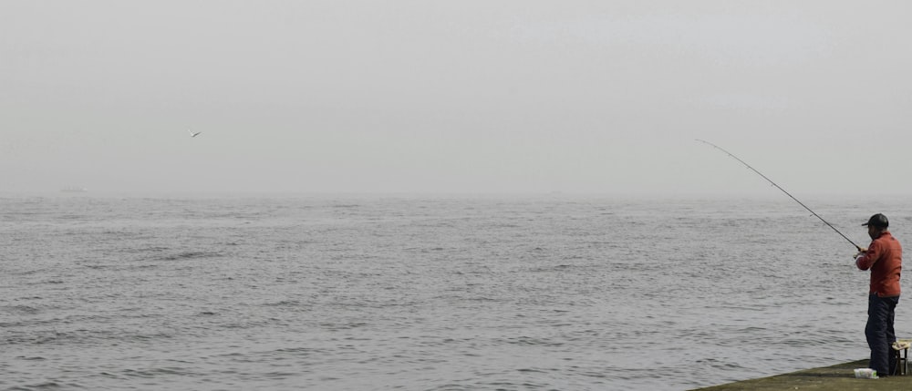 man fishing beside sea