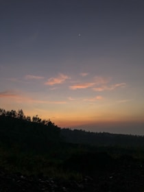 A serene landscape at dusk, with stars beginning to appear in the sky.