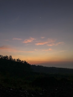 A serene landscape at dusk, with stars beginning to appear in the sky.