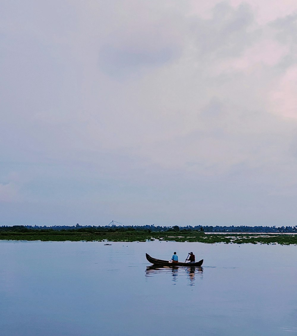two persons riding boat on body of water during day