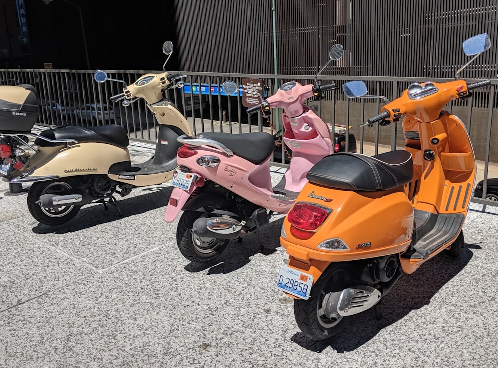 three assorted-color motor scooters