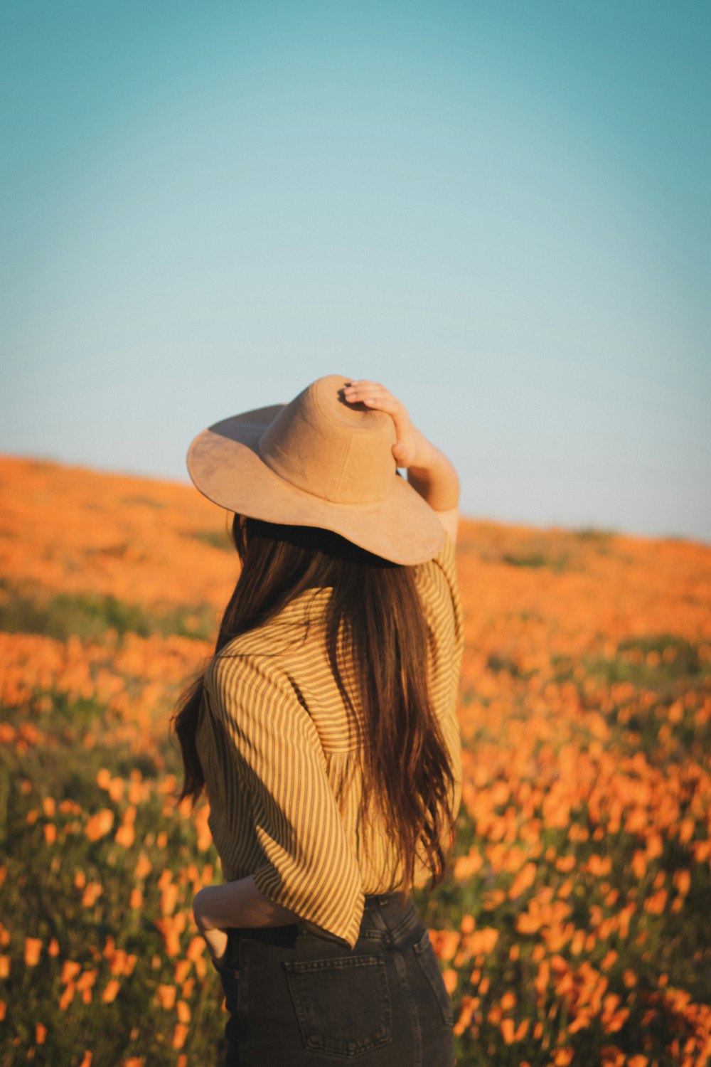 woman in white hat and beige top holding hat