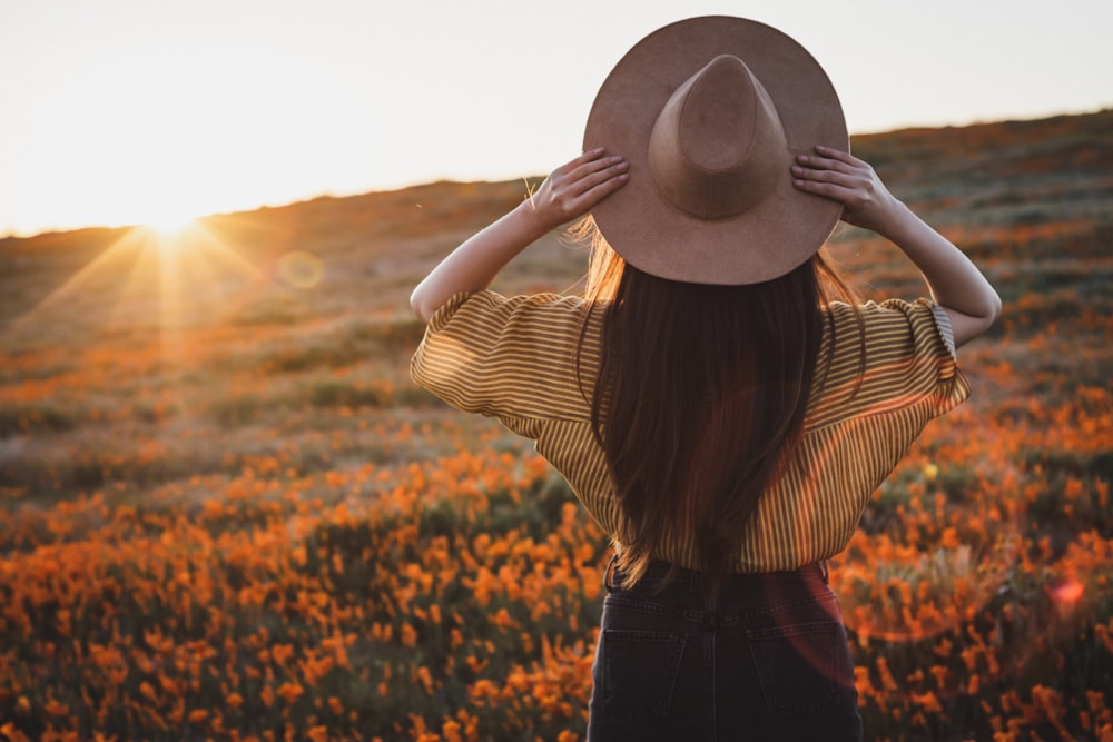 woman wearing yellow shirt and black bottoms and brown hat during golden hour