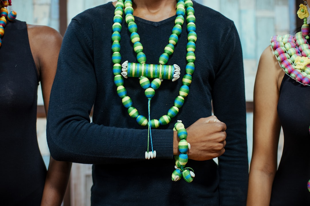 man wearing black long-sleeved shirt and beaded green necklace and bracelet