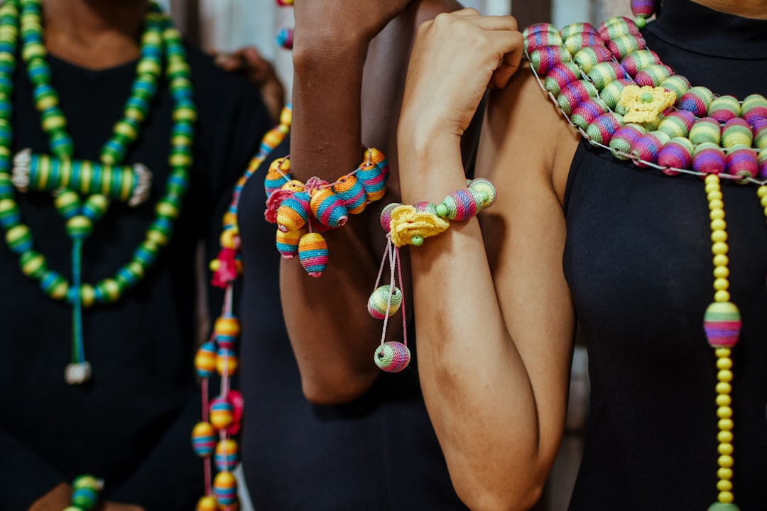 three women standing wearing multicolored bracelets