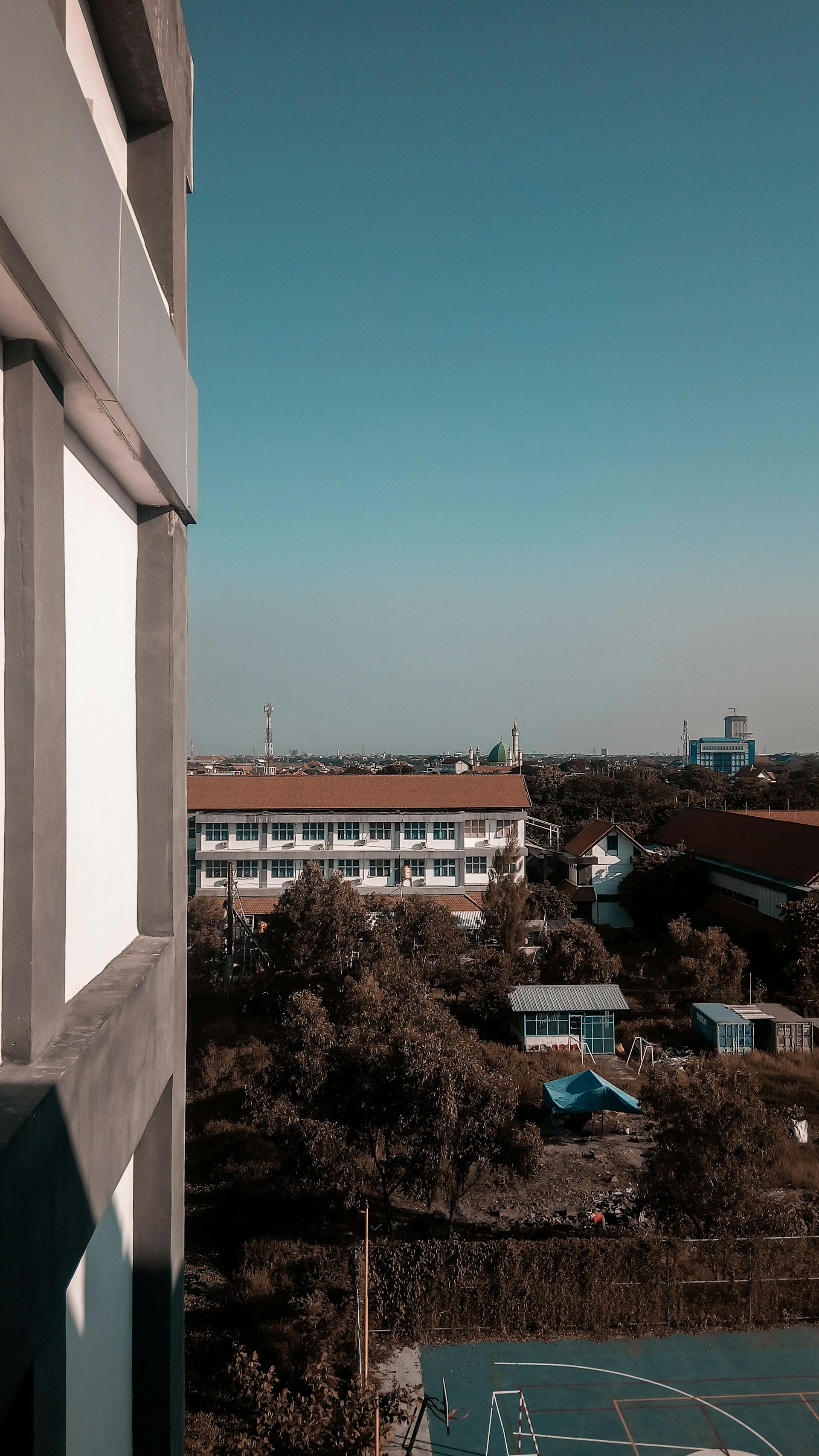 Panoramic view of basketball courts set in Villongo, with the nearby townscape of Grumello del Monte and Sarnico visible under a clear spring sky.