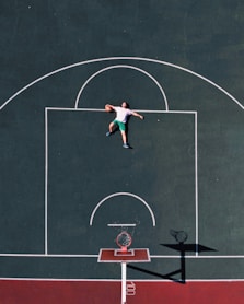 aerial photography of man lying on basketball court