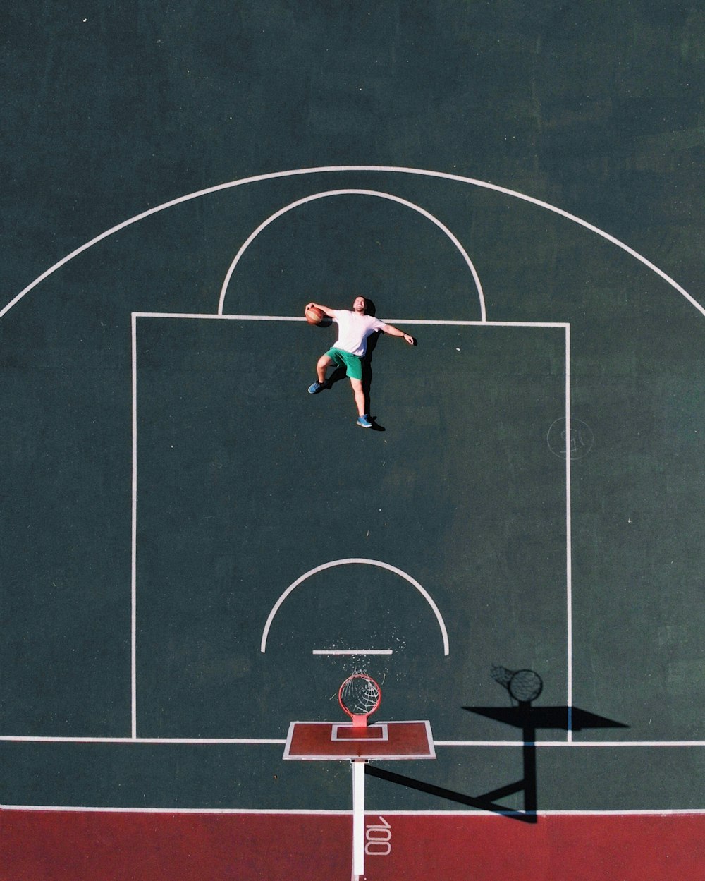 aerial photography of man lying on basketball court