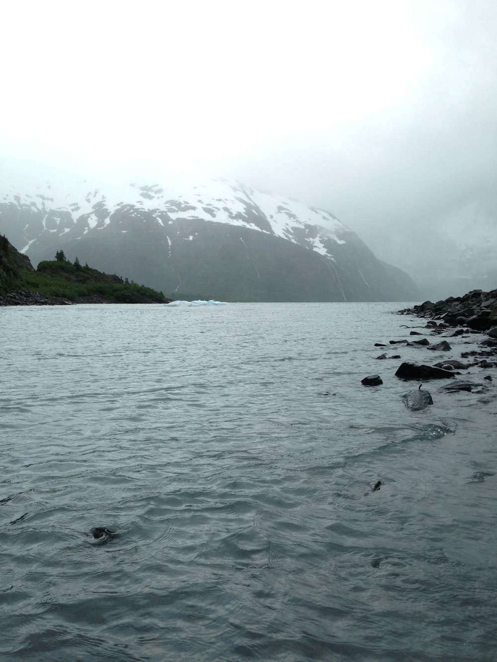 calm body of water near stones during daytime