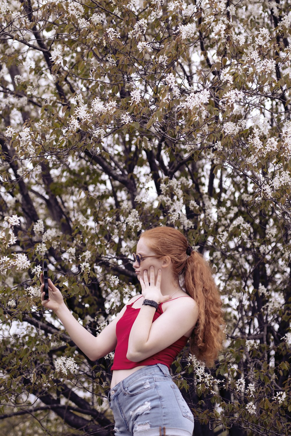 woman wearing red spaghetti-strap tank top and blue denim short shorts