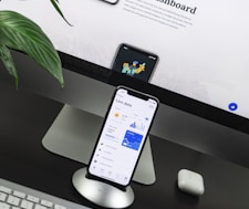 space gray iPhone X on stand near silver iMac and Apple Magic Keyboard