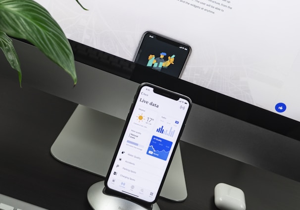 space gray iPhone X on stand near silver iMac and Apple Magic Keyboard