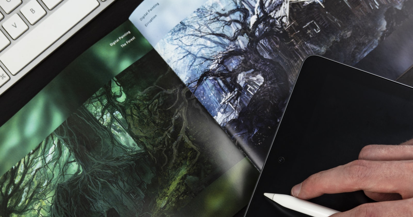 A designer's desk with digital cover art, a drawing tablet and stylus — creative craft and a design system taking shape