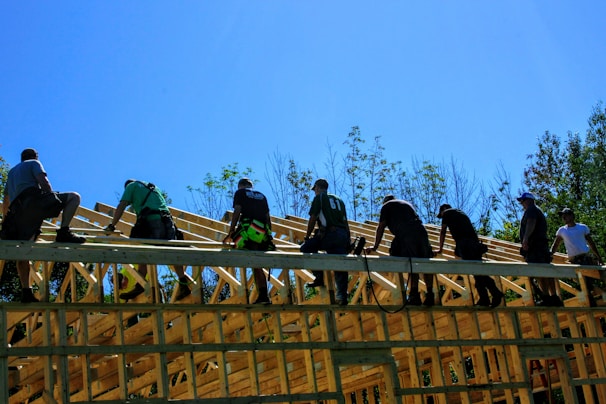 Close-up of hands fitting timber beams together on a sunny construction site.