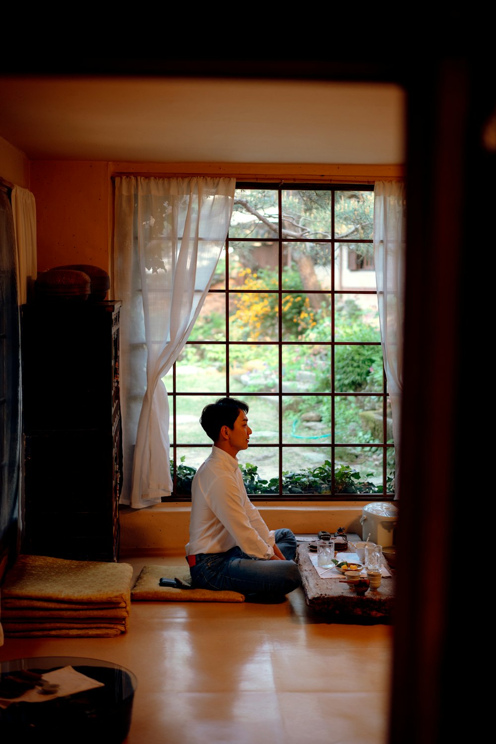 man sitting on floor by table and window