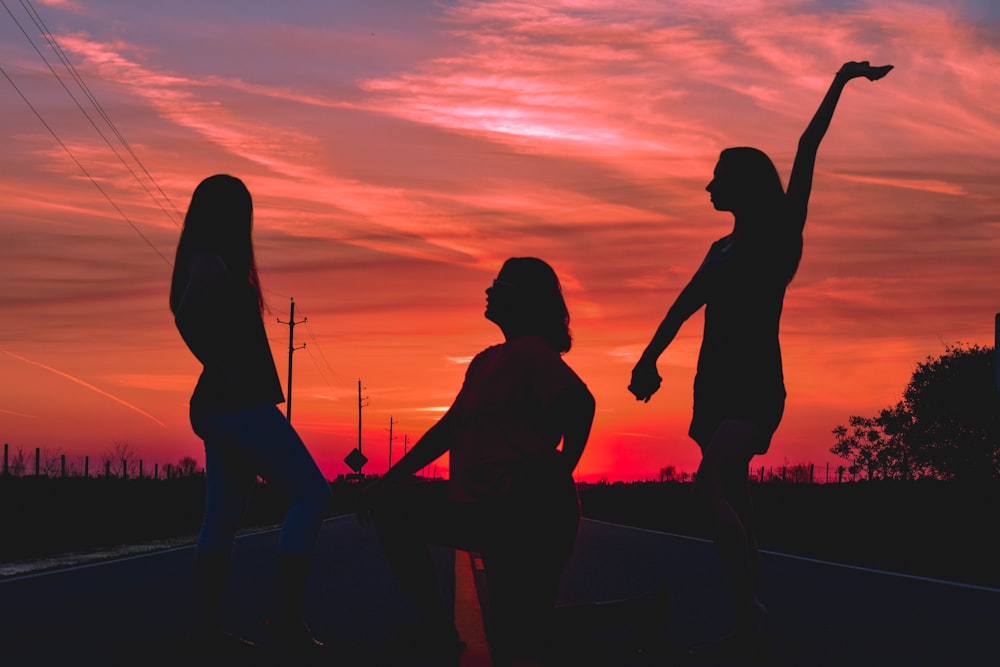 three women posing in the middle of the road during golden hour