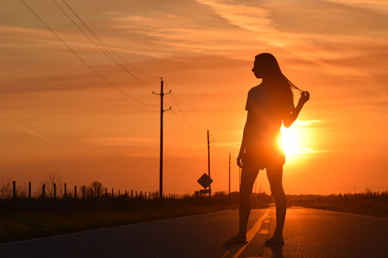 Corredora em silhueta na estrada contra o sol nascente